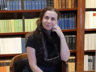 Person sitting in library, smiling at camera.