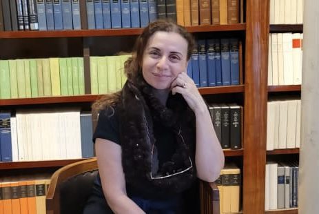 Person sitting in library, smiling at camera.