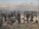 Crowd gathering in a dusty open area.
