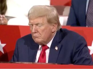 Man in suit sitting, eyes closed, thoughtful.