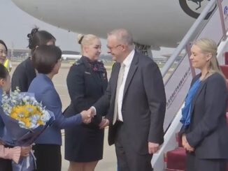 Delegation greeting on airport tarmac with flowers.