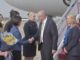 Delegation greeting on airport tarmac with flowers.