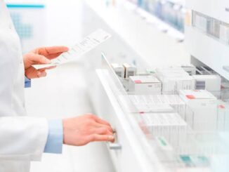 Pharmacist organizing medication in pharmacy drawer.