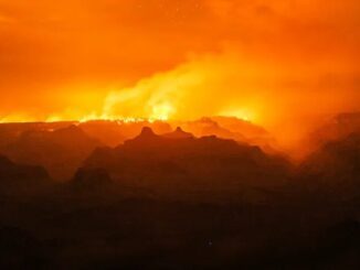 Orange sky over silhouetted mountainous landscape.
