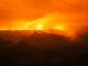 Orange sky over silhouetted mountainous landscape.