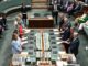 Politicians standing in a parliamentary chamber session.