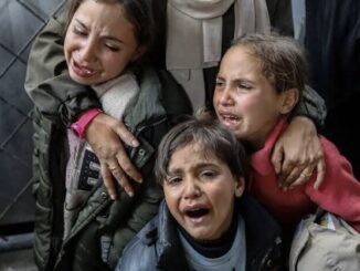 Three children crying, embraced by an adult.