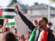 Protesters raising Palestinian flags and banners.