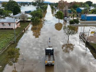 Truck driving through flooded street in town.