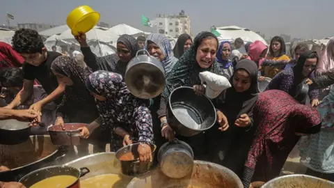 People gathering for food distribution in camp.