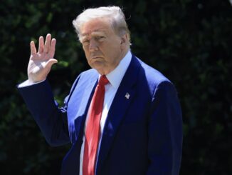 Man in suit waving outdoors, daytime scene.