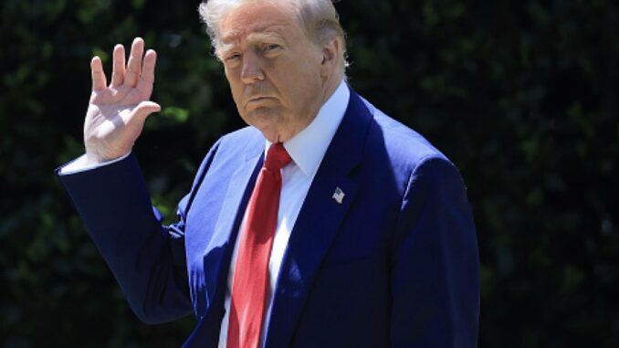 Man in suit waving outdoors, daytime scene.