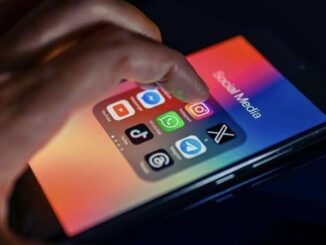 Hand touching smartphone with social media apps.