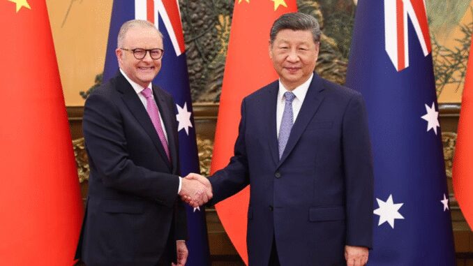 Two leaders shaking hands with flags behind.