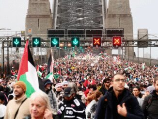 Crowd with flags on a busy bridge.