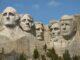 Mount Rushmore with five carved presidential faces.