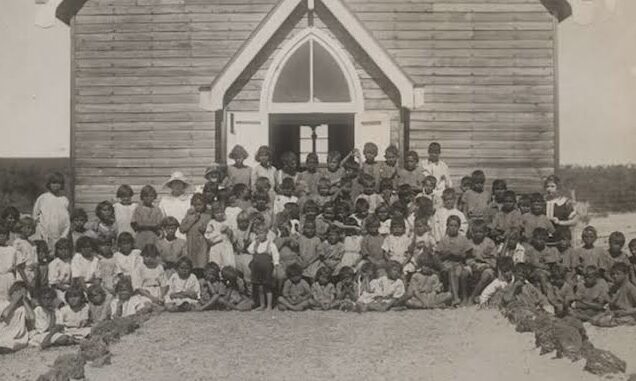 Large group of children outside wooden building. Large group of children outside wooden building.