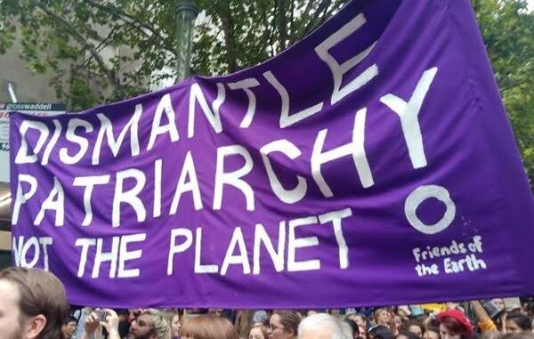 Protest banner reading "Dismantle Patriarchy Not Planet.