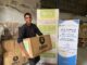 Man holding Oxfam food parcel, smiling.