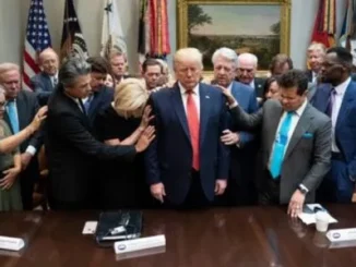 Group gathered around a central figure, praying.