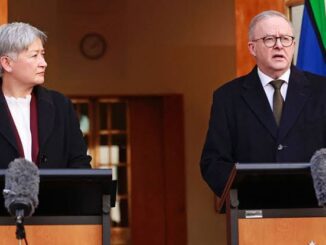 Two speakers at podiums with microphones and flag