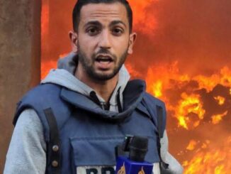 Reporter in front of large, raging fire.
