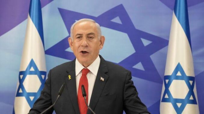 Man speaking in front of Israeli flags.