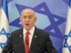 Man speaking in front of Israeli flags.