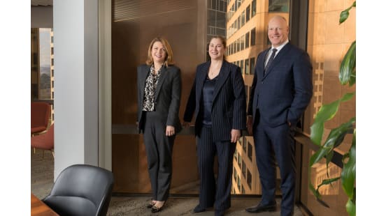 Three professionals standing in office setting.