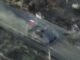 Aerial view of vehicle with flags on road.