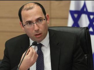 Man speaking at a meeting, Israeli flag.
