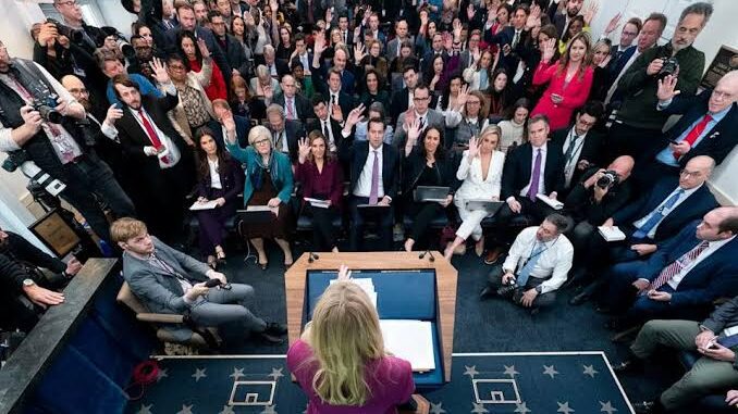 Press conference with seated audience and speaker.