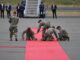 Soldiers preparing red carpet on airport runway.