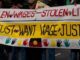Protesters holding banners demanding wage justice.