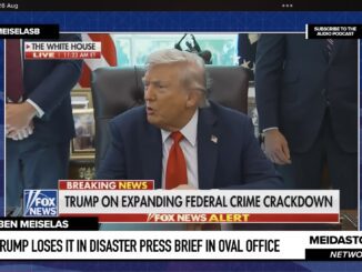 Man speaking at desk during press briefing.