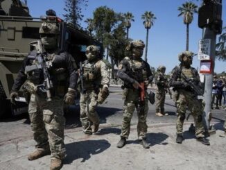 Armed soldiers in tactical gear on street.