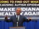 Speaker at podium with autism epidemic sign.