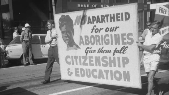 Protesters holding anti-apartheid sign for Aborigines.