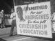 Protesters holding anti-apartheid sign for Aborigines.