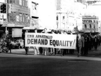 Protesters marching with "End Apartheid" banner.