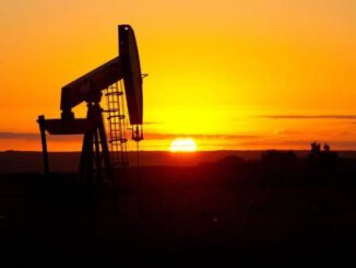 Oil pumpjack silhouette against sunset sky.