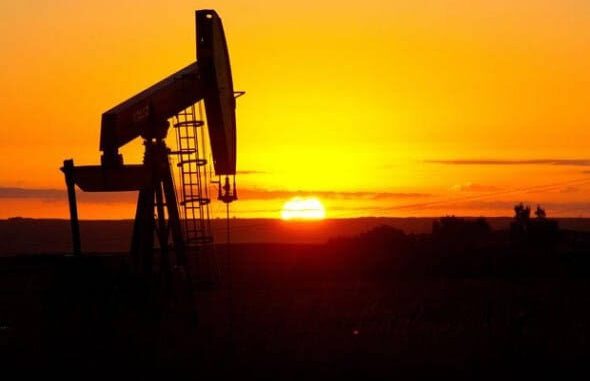 Oil pumpjack silhouette against sunset sky.