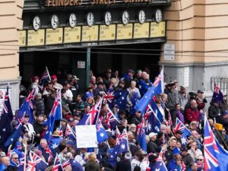 Crowd with flags outside building entrance.