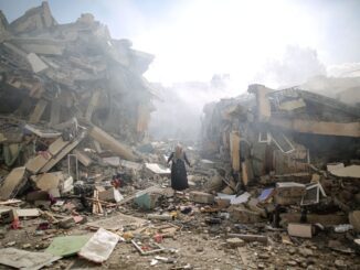 Person amidst collapsed buildings and debris.