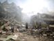 Person amidst collapsed buildings and debris.