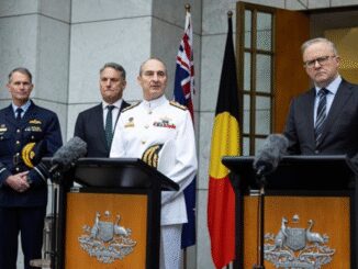Officials standing at podiums with flags behind.