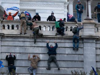 People climbing building during protest event.