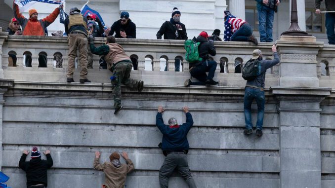 People climbing building during protest event.