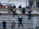 People climbing building during protest event.