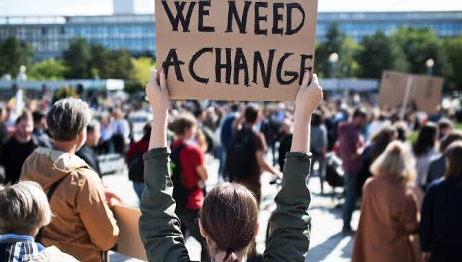 Person holding "We Need A Change" sign. Person holding "We Need A Change" sign.
